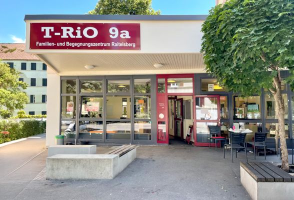 Ein hell beleuchteter Café-Raum mit Theke und Tischen und Stühlen vor einer gestreiften Wand.